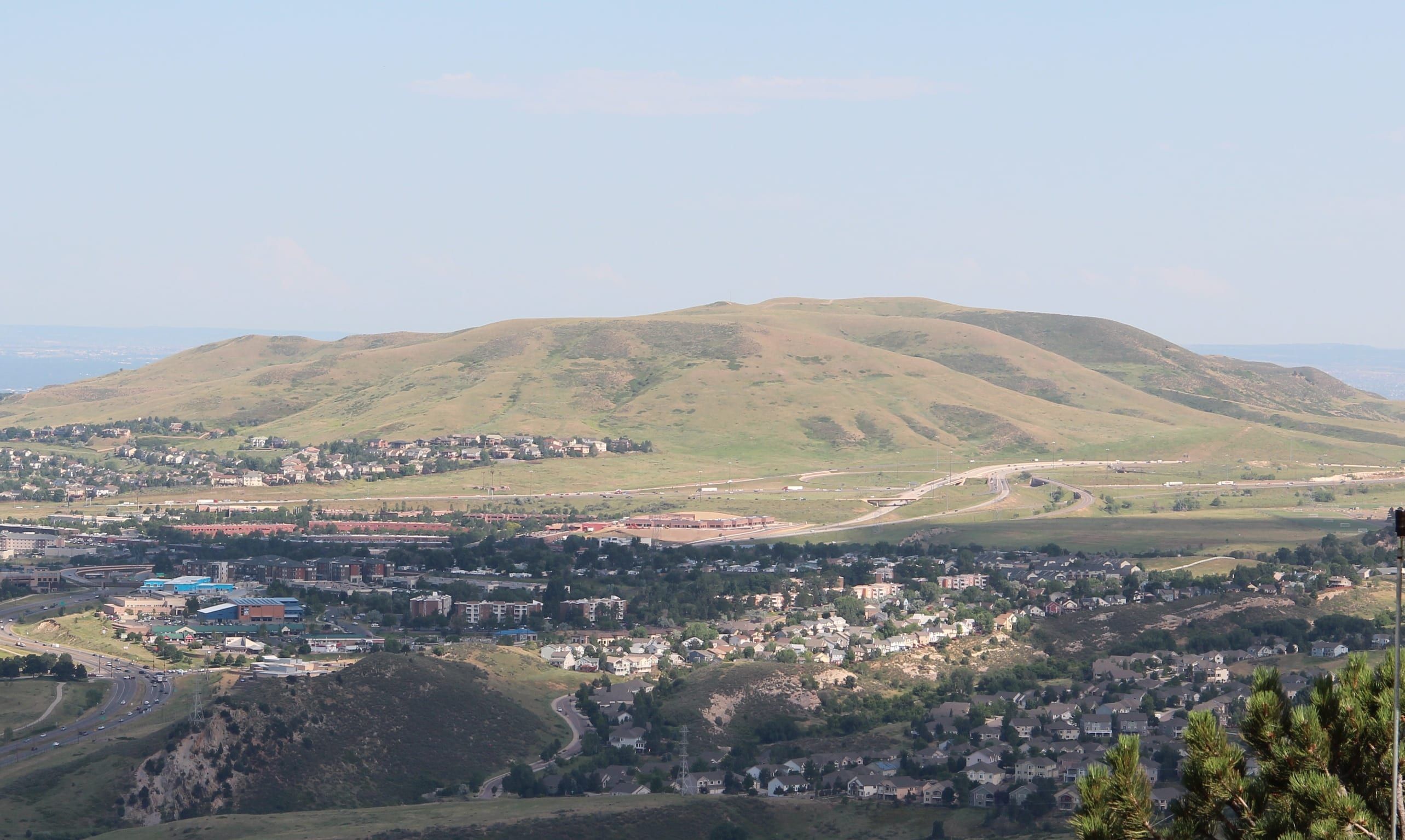 Green Mountain rising above the neighborhoods and roads of Lakewood, its grassy slopes under a pale, almost cloudless sky
